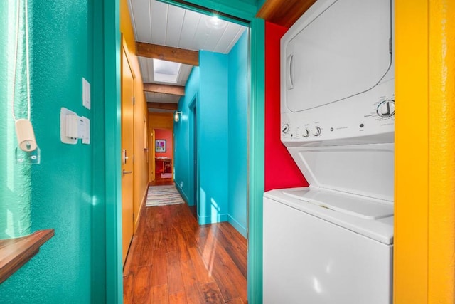 laundry room with a skylight, stacked washer / dryer, and dark hardwood / wood-style flooring