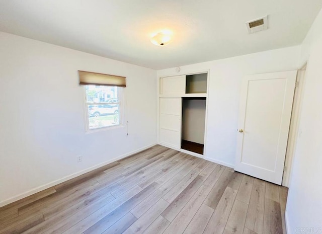 unfurnished bedroom with a closet and light wood-type flooring