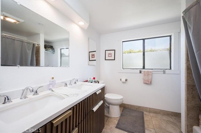 bathroom featuring double vanity, a sink, toilet, and tile patterned floors