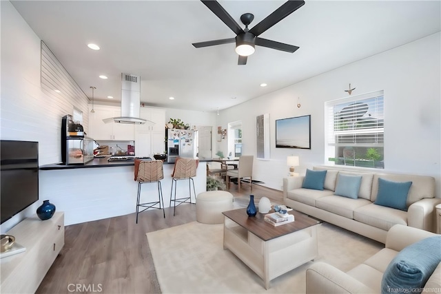 living area featuring recessed lighting, ceiling fan, a wealth of natural light, and wood finished floors