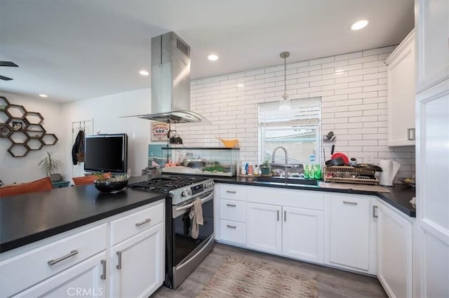 kitchen featuring white cabinets, dark countertops, island exhaust hood, a sink, and gas stove