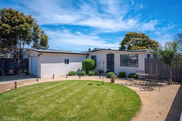 view of front of property with a front yard, a patio area, fence, and stucco siding