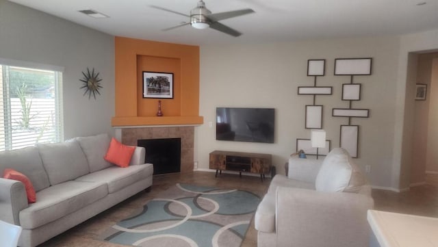 living room with ceiling fan and a tile fireplace