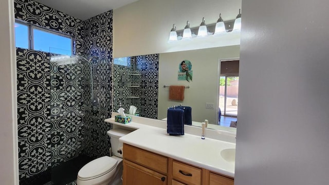 bathroom featuring vanity, toilet, and tiled shower