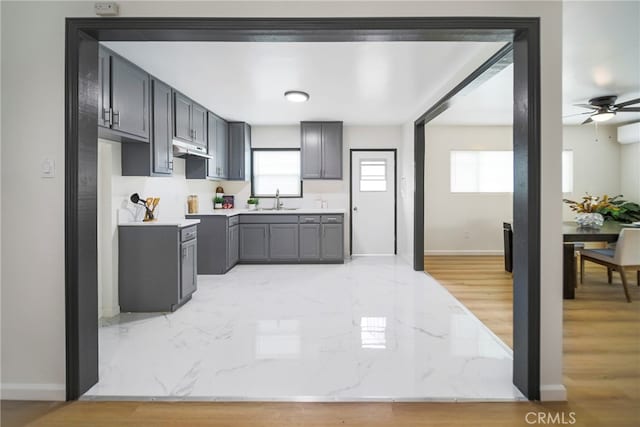 kitchen featuring gray cabinets, sink, light wood-type flooring, and a healthy amount of sunlight