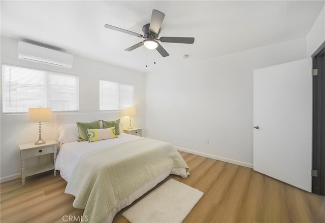 bedroom featuring ceiling fan, an AC wall unit, and light wood-type flooring