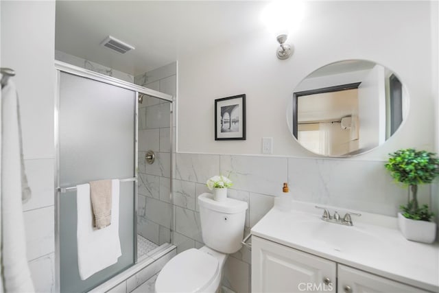 bathroom featuring vanity, toilet, walk in shower, and tile walls