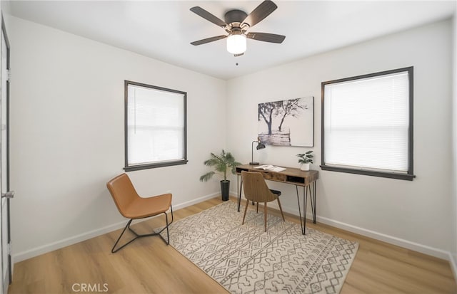 home office with light hardwood / wood-style floors and ceiling fan