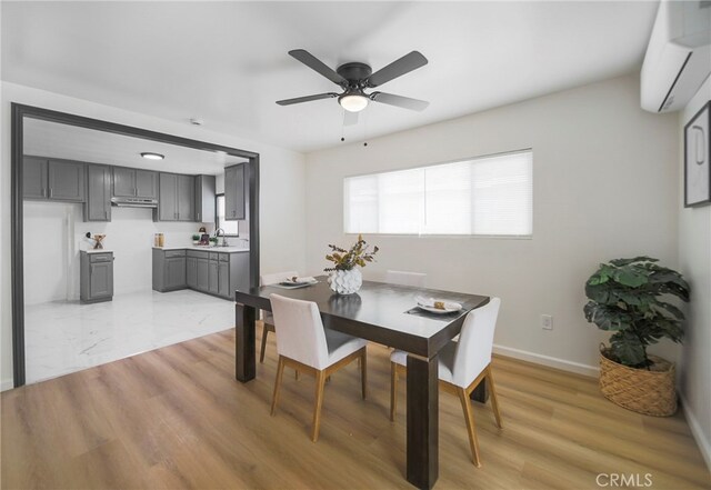 dining room with sink, a wall mounted air conditioner, light wood-type flooring, and ceiling fan