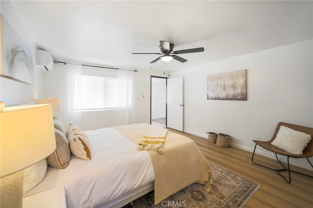 bedroom with ceiling fan, hardwood / wood-style flooring, and a wall unit AC