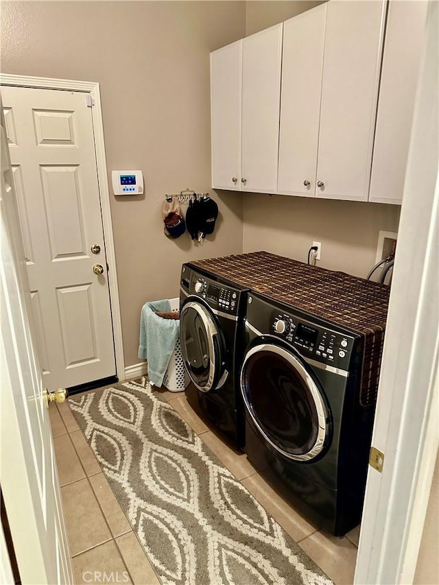 washroom with washer and clothes dryer, light tile patterned flooring, and cabinets