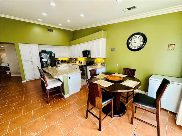 kitchen featuring crown molding, an island with sink, appliances with stainless steel finishes, light stone counters, and white cabinetry