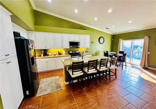 kitchen with white cabinetry, stainless steel appliances, light stone counters, vaulted ceiling, and a center island with sink