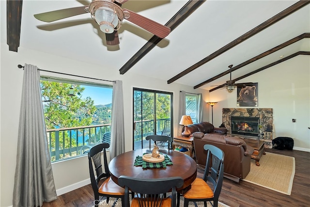 dining area with vaulted ceiling with beams, dark hardwood / wood-style floors, and a stone fireplace