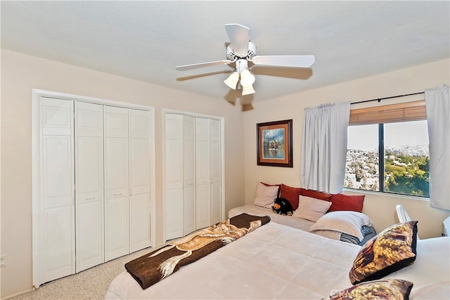 carpeted bedroom with ceiling fan, a textured ceiling, and two closets