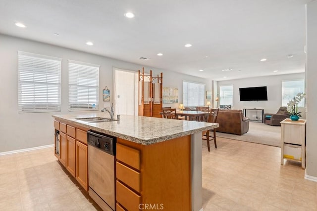 kitchen with dishwasher, a center island with sink, light stone counters, and sink