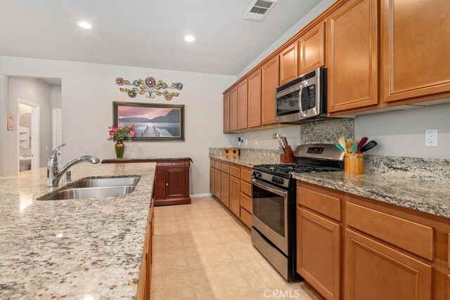 kitchen with light stone countertops, sink, and stainless steel appliances