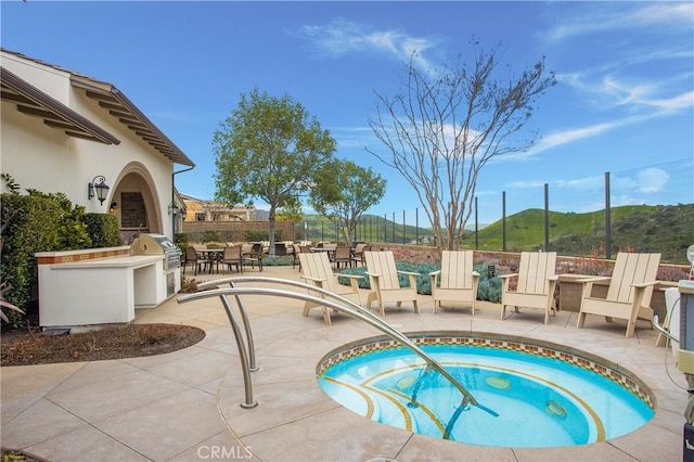 view of swimming pool featuring an in ground hot tub, a patio area, a grill, and a mountain view