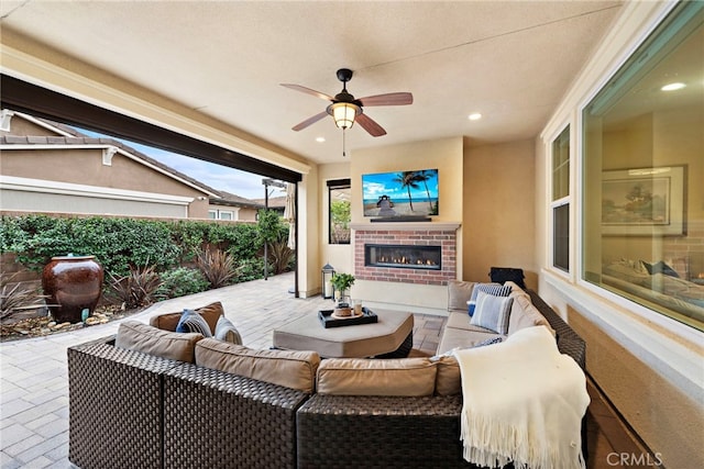 view of patio with ceiling fan and an outdoor living space with a fireplace