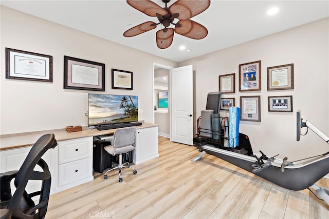 office area featuring light wood-type flooring, ceiling fan, and built in desk