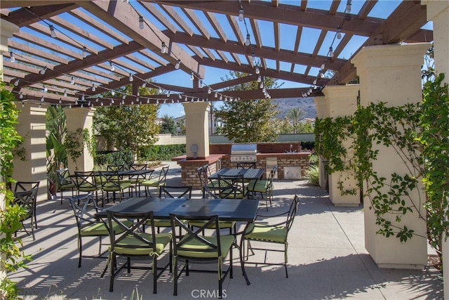 view of patio with exterior kitchen, a pergola, and a grill