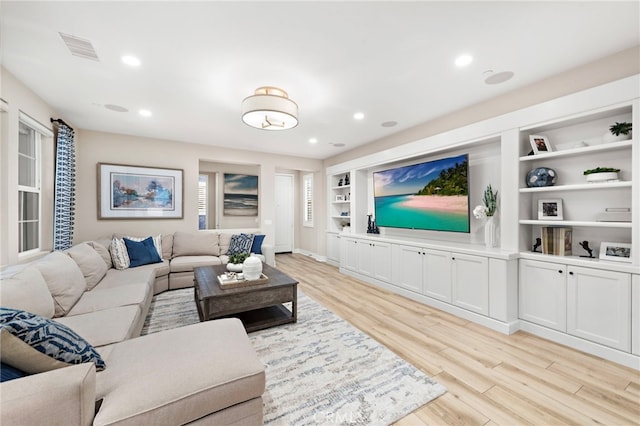 living room with light hardwood / wood-style flooring and built in shelves