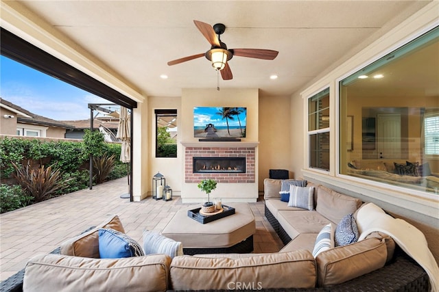 view of patio / terrace with ceiling fan and an outdoor living space with a fireplace