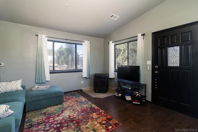 living room with lofted ceiling, a wood stove, and wood-type flooring