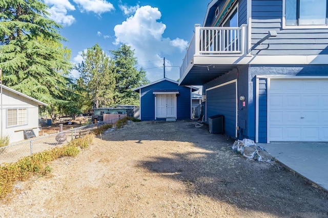 view of property exterior with a storage unit, a balcony, and a garage