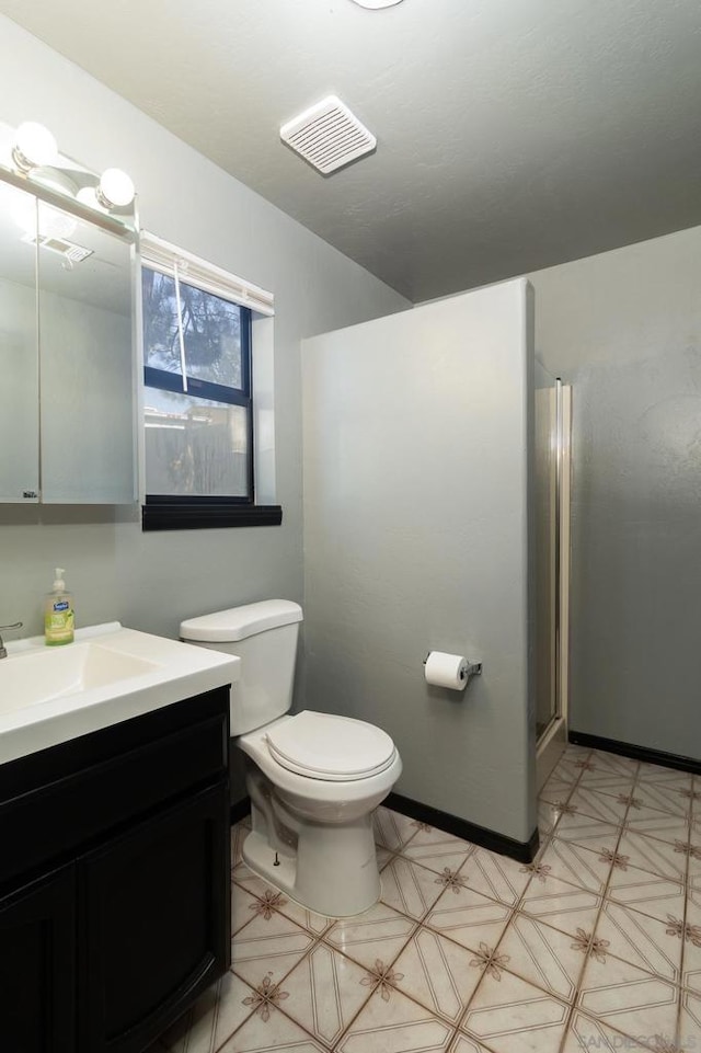 bathroom featuring a shower with door, vanity, and toilet