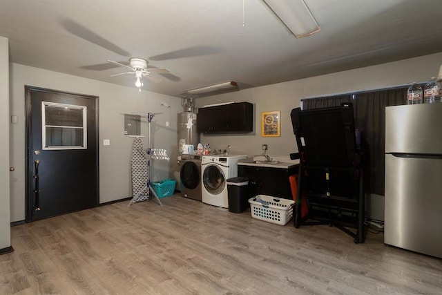 washroom with light hardwood / wood-style floors, water heater, washing machine and clothes dryer, and ceiling fan