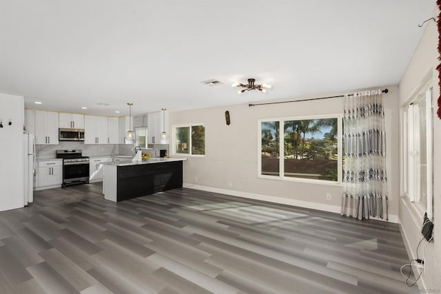 kitchen with white cabinetry, decorative light fixtures, stainless steel appliances, and dark hardwood / wood-style floors