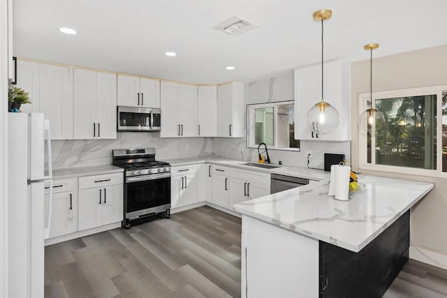 kitchen with white cabinetry, appliances with stainless steel finishes, decorative light fixtures, and kitchen peninsula