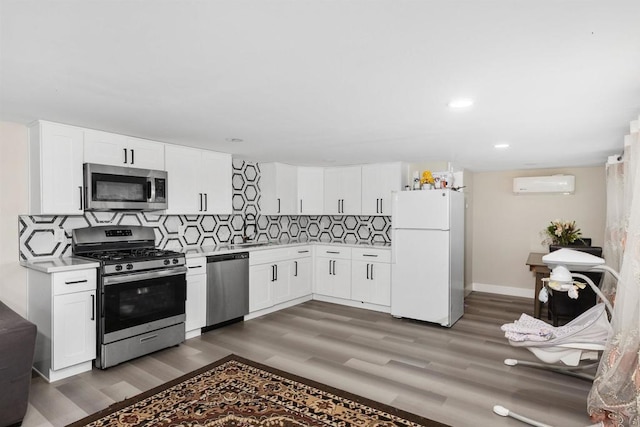 kitchen with appliances with stainless steel finishes, backsplash, a wall unit AC, white cabinets, and dark hardwood / wood-style floors