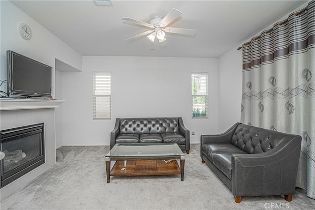 living room with light carpet, ceiling fan, and a tiled fireplace