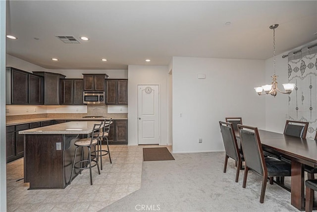 kitchen featuring a kitchen breakfast bar, stainless steel appliances, pendant lighting, a notable chandelier, and a kitchen island