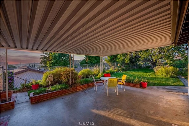 patio terrace at dusk featuring a yard