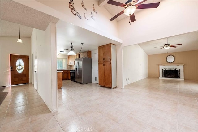 unfurnished living room with ceiling fan, light tile patterned floors, high vaulted ceiling, and a brick fireplace