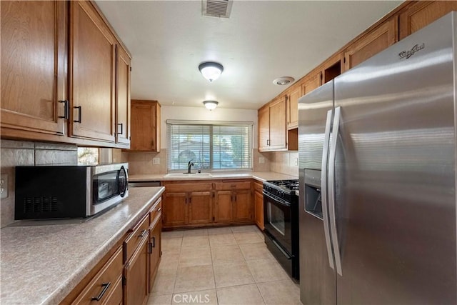 kitchen with backsplash, sink, light tile patterned floors, and stainless steel appliances