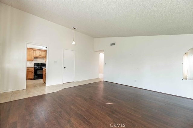 unfurnished living room with light hardwood / wood-style flooring, high vaulted ceiling, and a textured ceiling