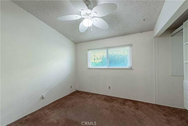 unfurnished bedroom featuring ceiling fan, dark carpet, and a textured ceiling