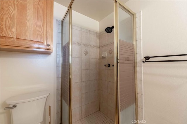 bathroom featuring toilet and a shower with door