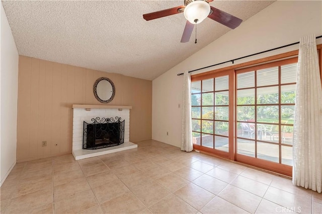 unfurnished living room with ceiling fan, a brick fireplace, lofted ceiling, a textured ceiling, and light tile patterned floors