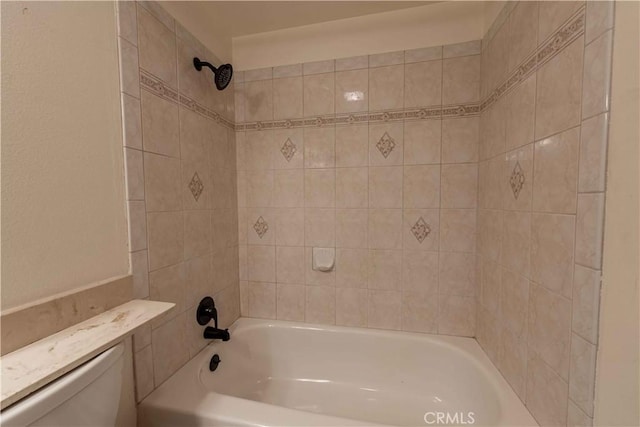 bathroom with toilet and tiled shower / bath