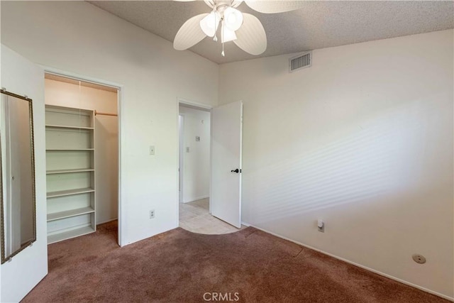 unfurnished bedroom featuring ceiling fan, a closet, light colored carpet, and a textured ceiling