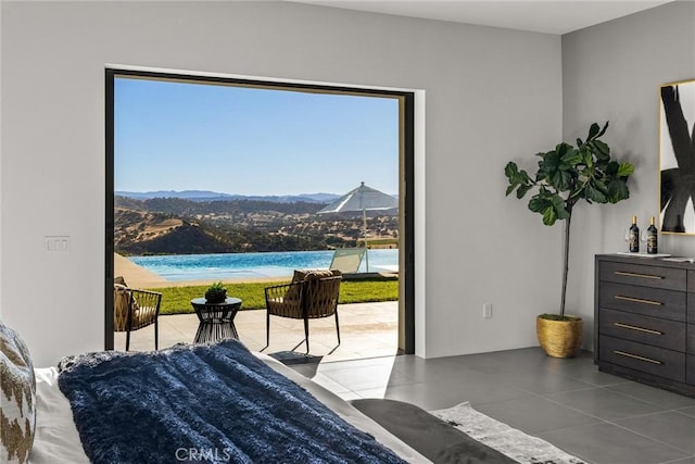 bedroom with a mountain view, tile patterned flooring, and access to exterior
