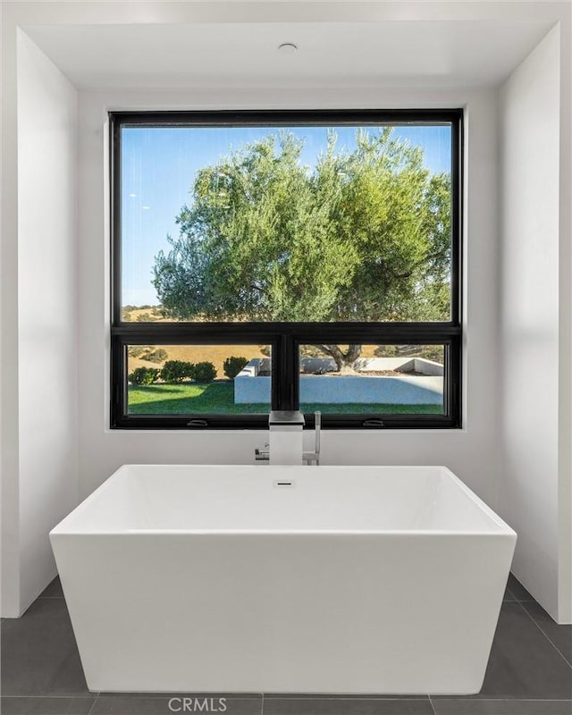 full bath featuring a soaking tub and tile patterned flooring