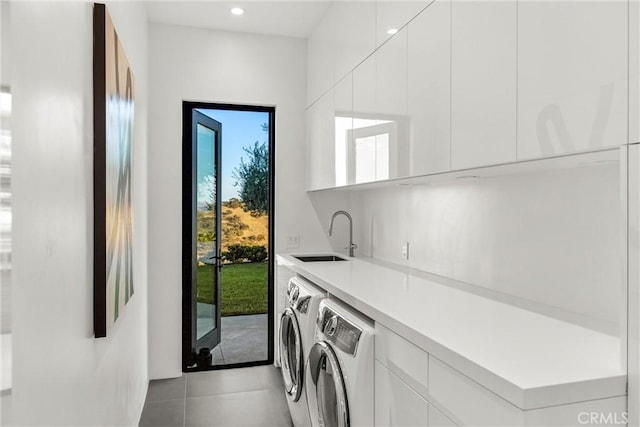 laundry area with cabinets, independent washer and dryer, sink, and light tile patterned floors