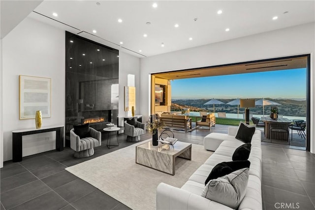 tiled living area featuring a large fireplace, recessed lighting, and a high ceiling