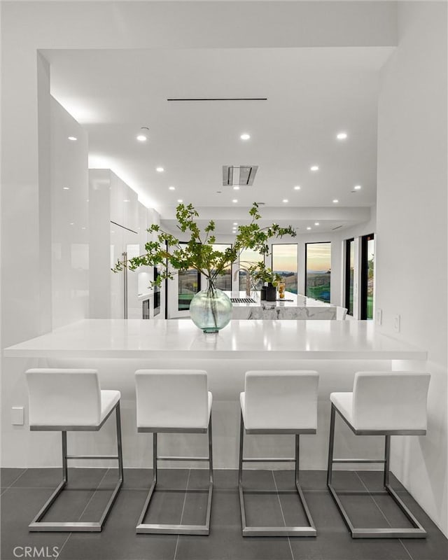 kitchen with a breakfast bar area, kitchen peninsula, and dark tile patterned floors